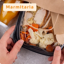 Mãos segurando embalagem de marmita com vegetais e carne, acompanhada de suco, representando serviço de marmitaria.