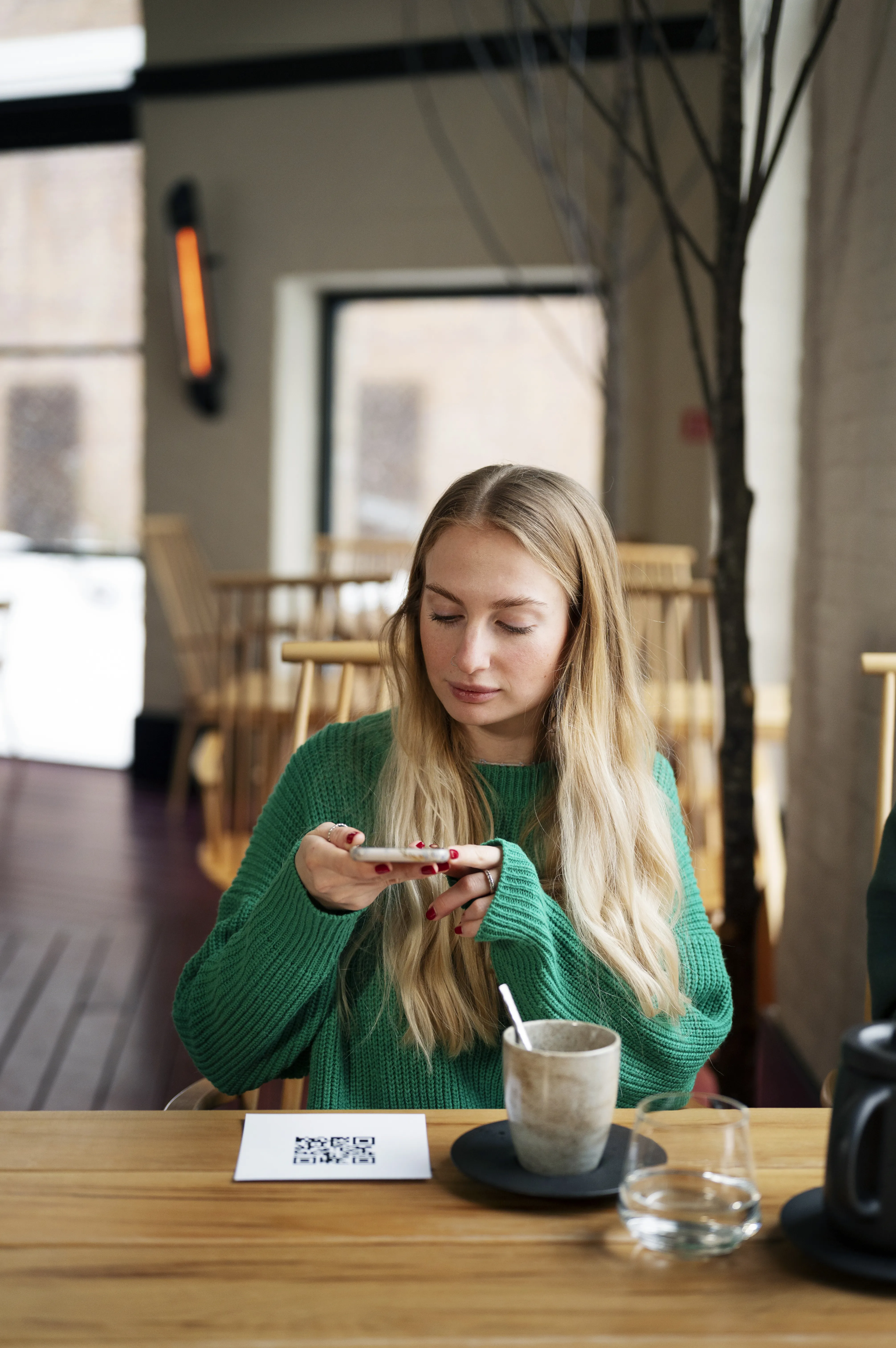 Cliente escaneando código QR na mesa de cafeteria, demonstrando integração de tecnologia para autoatendimento via sistema para cafeterias.